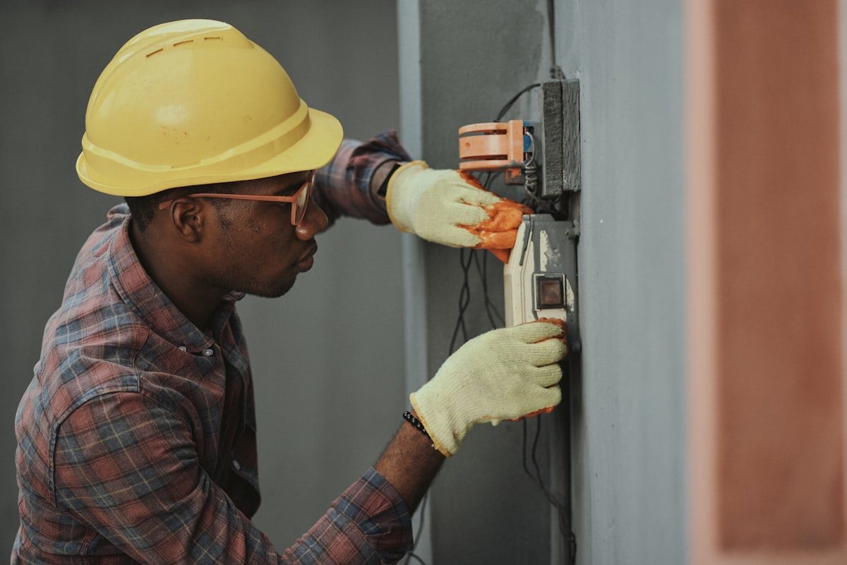 Technician in a hard hat servicing equipment on a wall